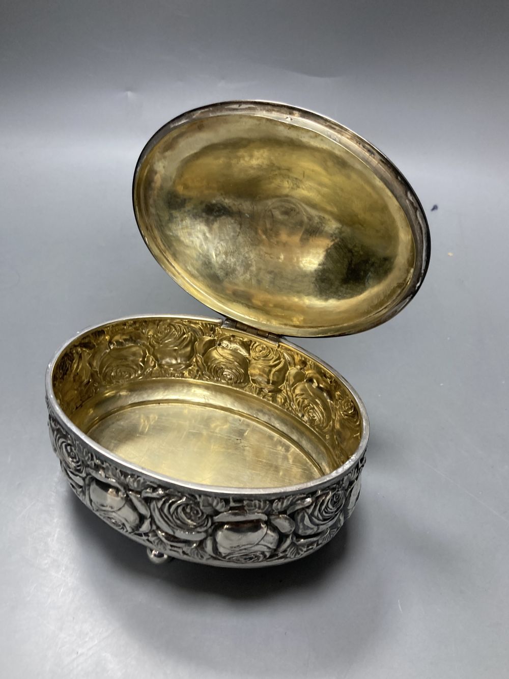 An early to mid 20th century continental 800 standard white metal oval lidded box, embossed with roses,